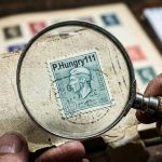 Close-up of a P.Hungry111 postage stamp being examined with a magnifying glass for valuation