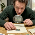 High-resolution scan of a rare investment-grade marine life postal stamp examined with a magnifying glass