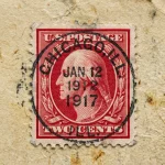 A close-up of a red 2 cent George Washington postage stamp used in early 20th century.